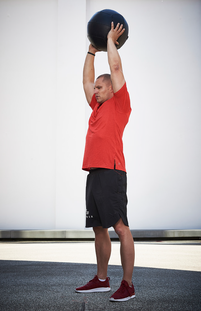 Un homme réalisant des medball slams.