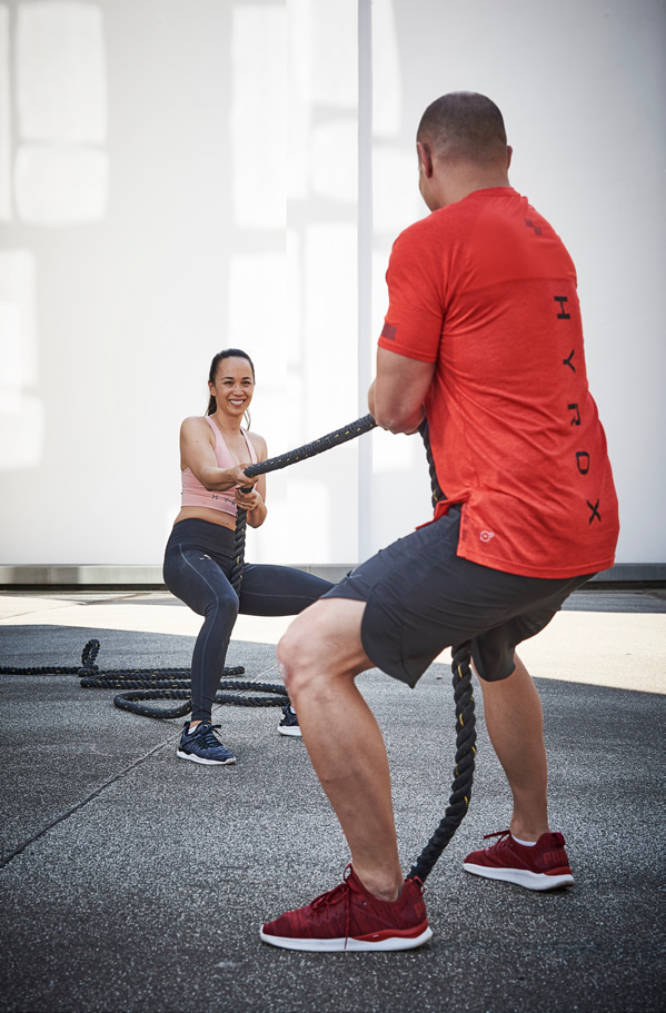 Un homme et une femme tirant une corde pour simuler l'effort du sled pull.